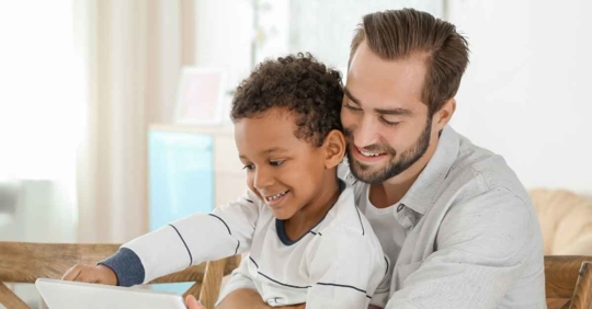 A man helping a child write something