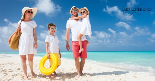 A family of four walking on the beach.