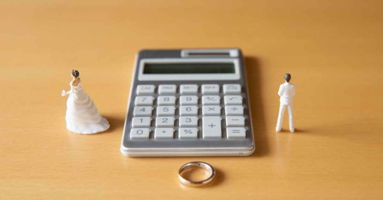 A calculator next to a wedding ring and separated figures of a husband and wife