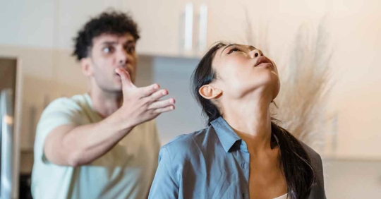 A woman rolling her eyes and looking upward as her husband is arguing with her