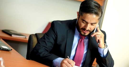 A lawyer sitting at his desk while on his phone