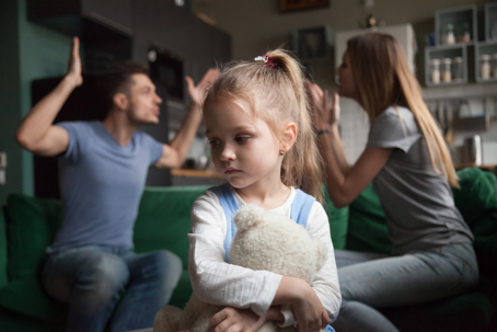 sad child with parents arguing behind her