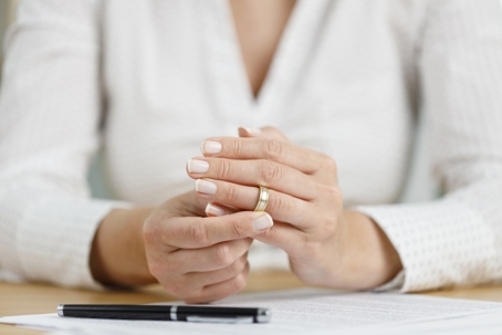 woman removing wedding ring after signing divorce papers