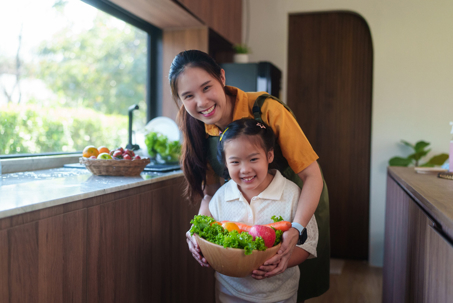mother and daughter in the kitchen holding a bowl of vegetables