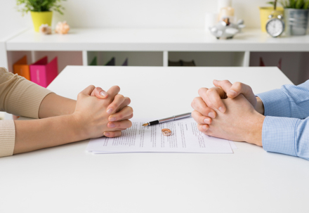 couple facing each other about to sign divorce papers